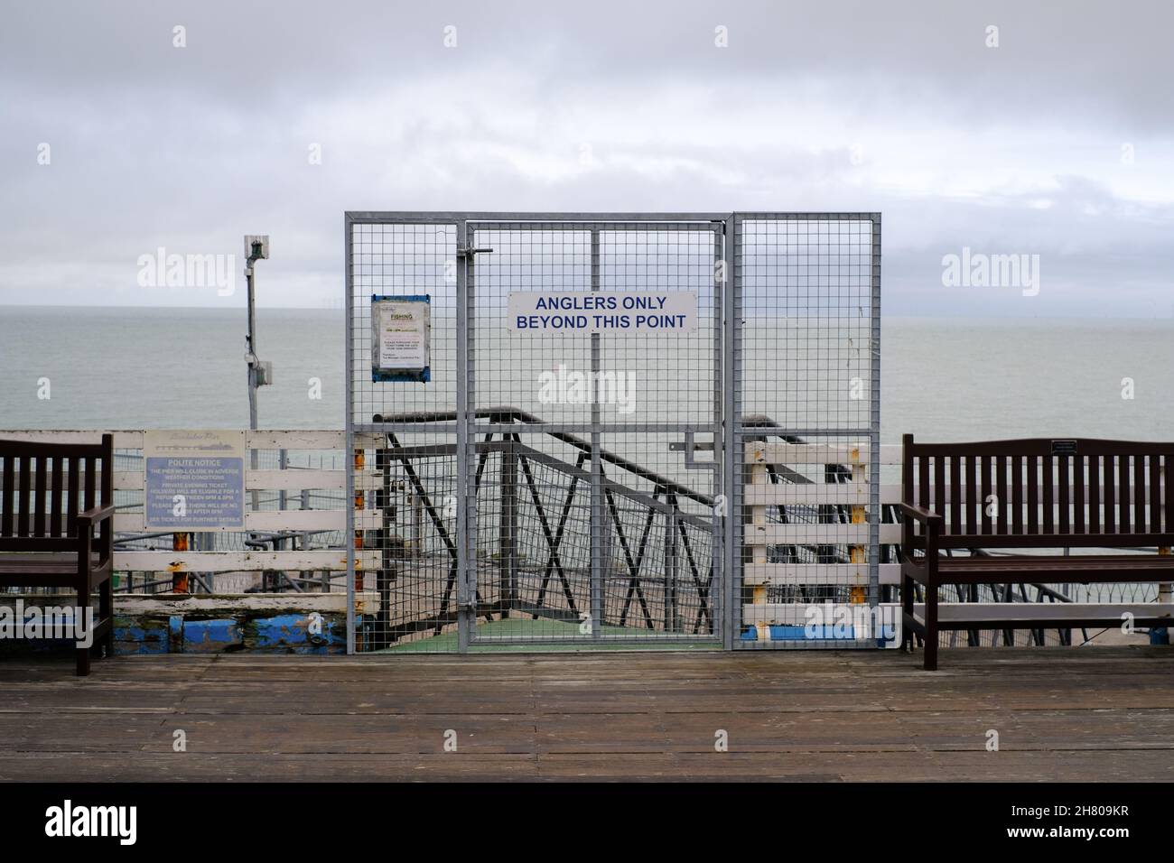 Una grande barriera metallica alla fine del molo di Llandudno proibisce a tutti tranne i pescatori di procedere. Un condimento freddo e grigio si trova oltre. Foto Stock