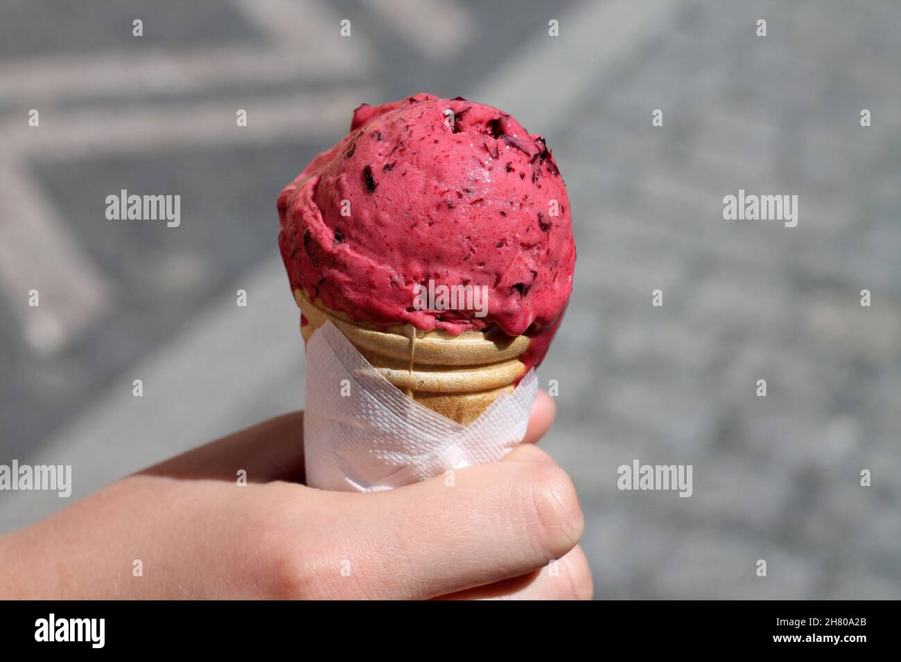Cono gelato in mano. Dessert di frutti di bosco congelati rosa. Foto Stock