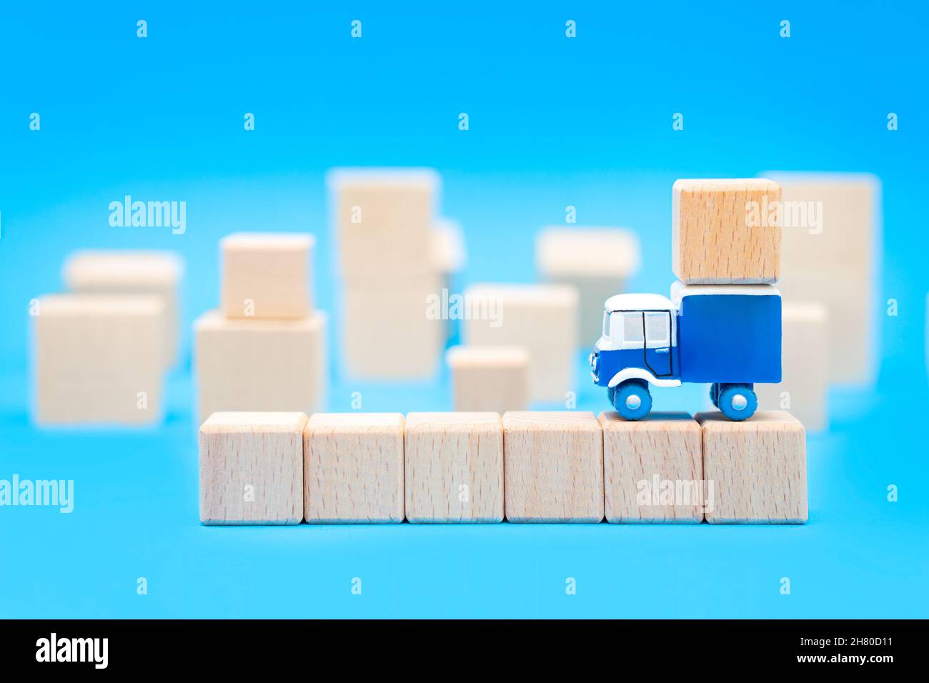 Carrello giocattolo in piedi sulla parte superiore di una fila di blocchi di lettere vuoti con un gruppo di cubi di legno sullo sfondo. Concetto di servizio di trasferimento. Foto Stock