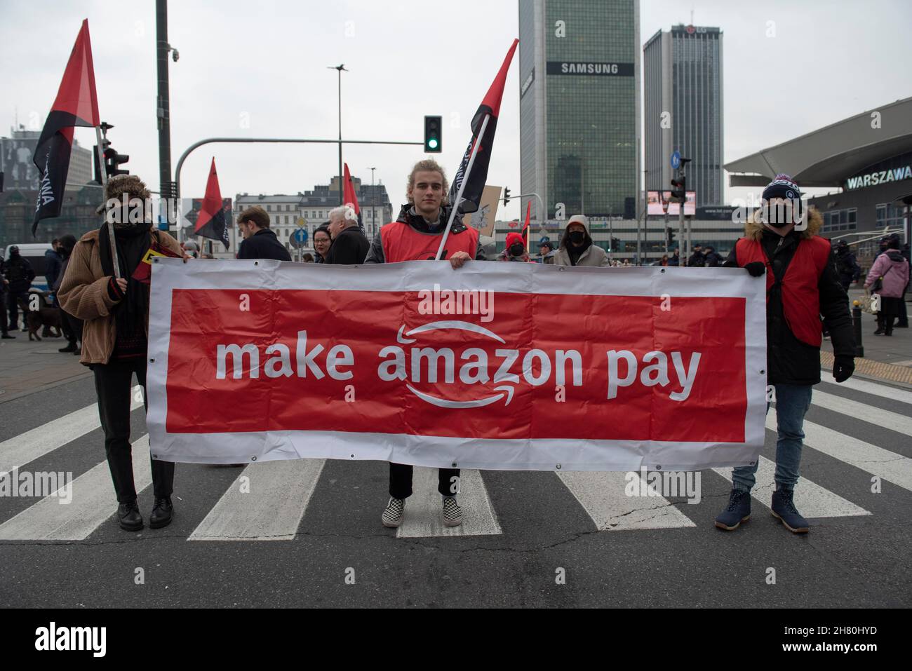 Varsavia, Polonia. 26 novembre 2021. I dimostranti hanno un banner durante una protesta contro il trattamento equo dei dipendenti da parte di Amazon il 26 novembre 2021 a Varsavia, Polonia. Alcune decine di persone si sono radunate nel centro di Varsavia sotto lo slogan "Stop patho-trade" e "Make Amazon Pay", chiedendo al gigante della tecnologia di fornire migliori condizioni di lavoro per i suoi dipendenti e di ridurre la sua impronta di carbonio in espansione. Lanciato il Black Friday, gli attivisti forniscono un elenco di richieste per Amazon e altre multinazionali, che includono l'aumento della retribuzione per i lavoratori nei magazzini di Amazon, giusto tra Foto Stock