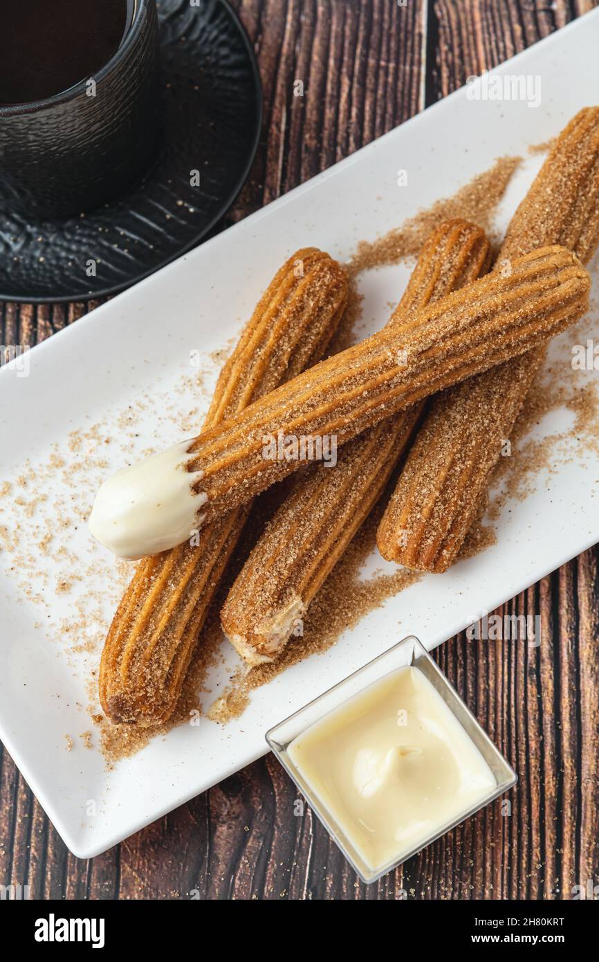 Churros caldi con salsa di cioccolato su tavola di legno. Foto Stock