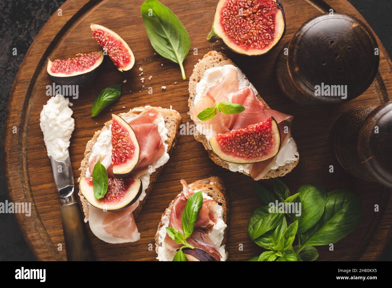 Bruschetta con prosciutto e formaggio italiano e fichi su un asse di legno, vista dall'alto Foto Stock