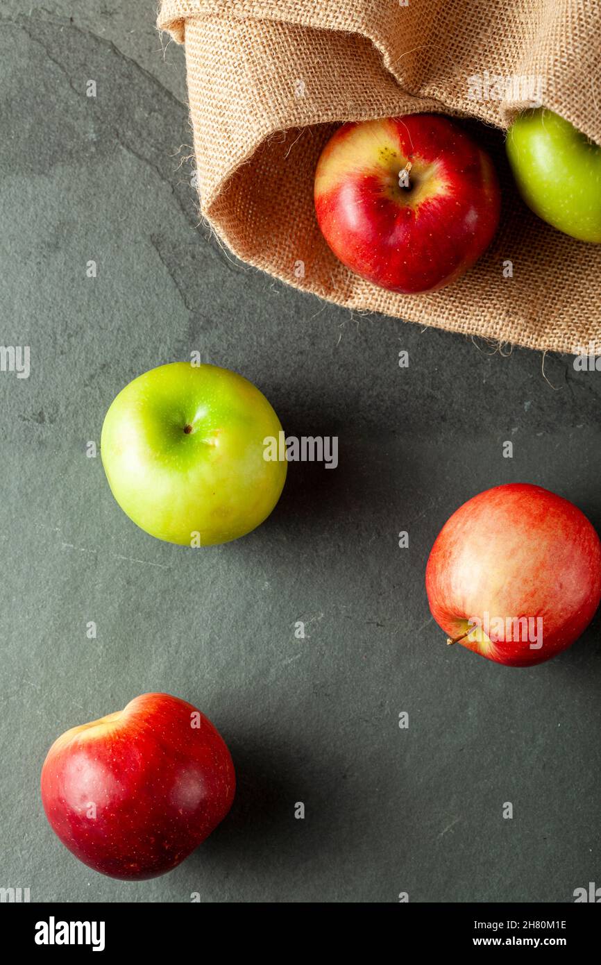 mele di diverse varietà sono viste su pietra scura e sfondo di legno. Ci sono mele da crostata verde e mele dolci rosse viste fianco a fianco. Concep Foto Stock