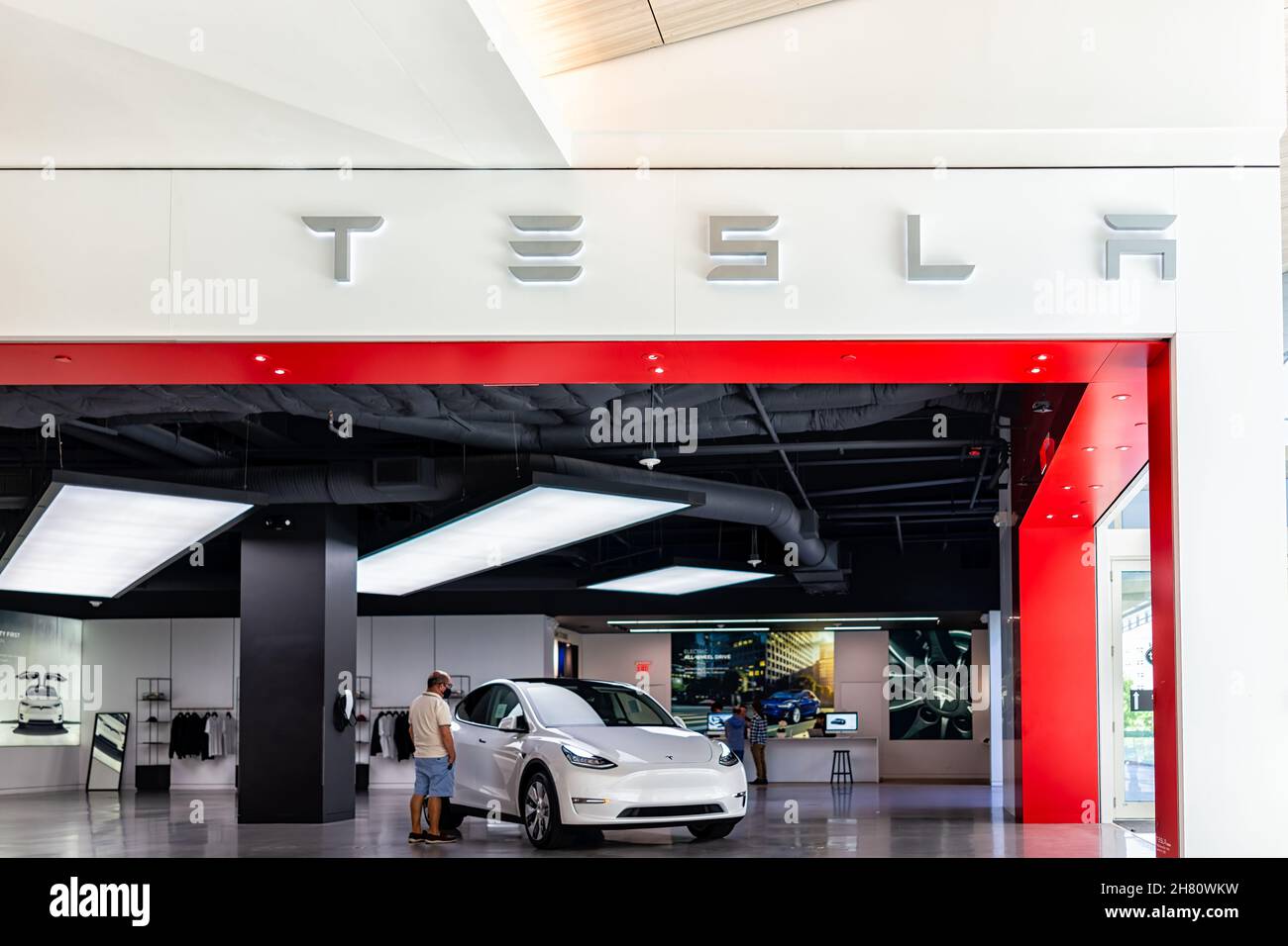 Miami, USA - 19 luglio 2021: Cartello per il negozio Tesla con clienti che guardano veicoli elettrici all'interno del centro commerciale Aventura a fioretto Foto Stock