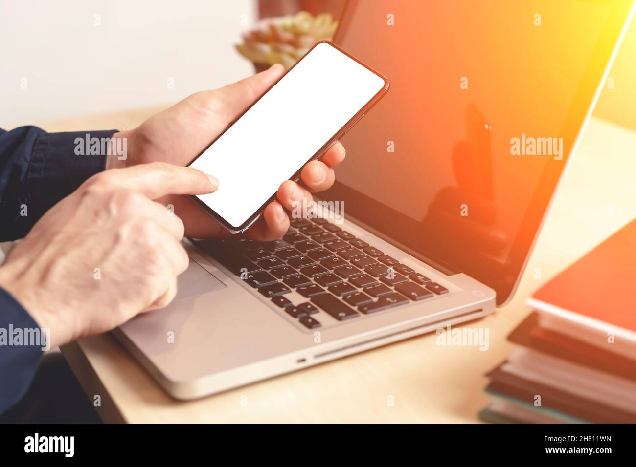 Telefono e computer portatile a portata di mano sul desktop in ufficio o a casa. Mockup dello schermo vuoto dello smartphone. Utilizzo del Web, dello shopping e delle app. Foto di alta qualità Foto Stock