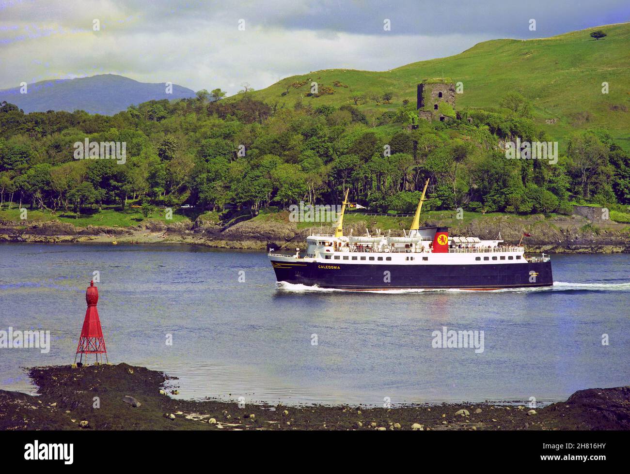 La MV Caledonia passa il Castello di Dunollie mentre esce dalla baia, Oban anni '70 Foto Stock