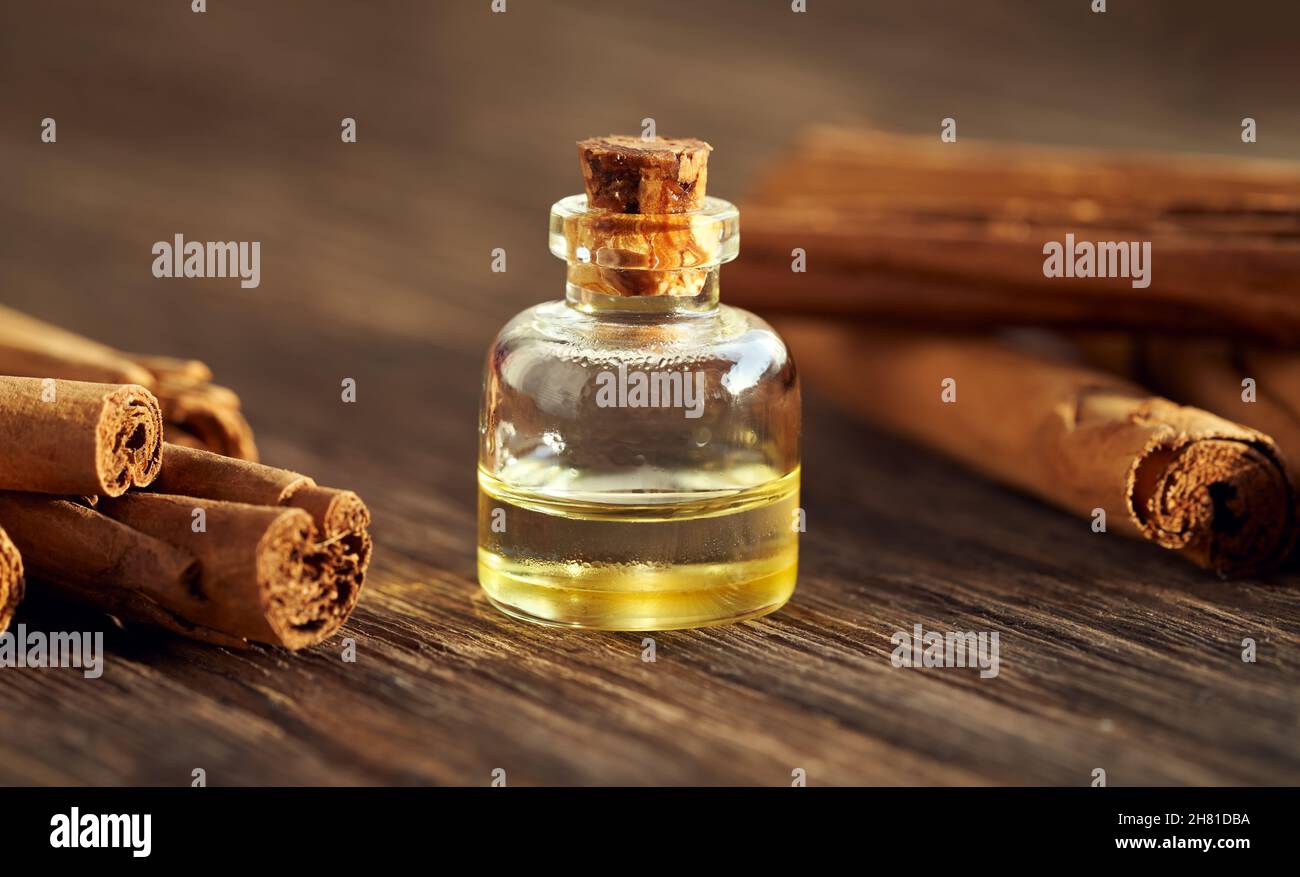 Una bottiglia di olio essenziale aromatherapy con cannella vera o verum Cinnamomum bastoni su un tavolo di legno Foto Stock