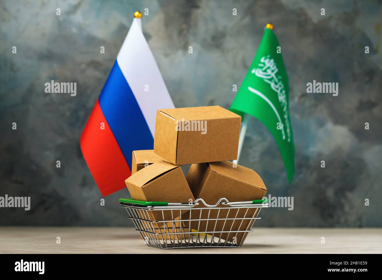 Varie scatole in un paniere alimentare e due bandiere su un background astratto, il concetto di commercio tra Arabia Saudita e Russia Foto Stock