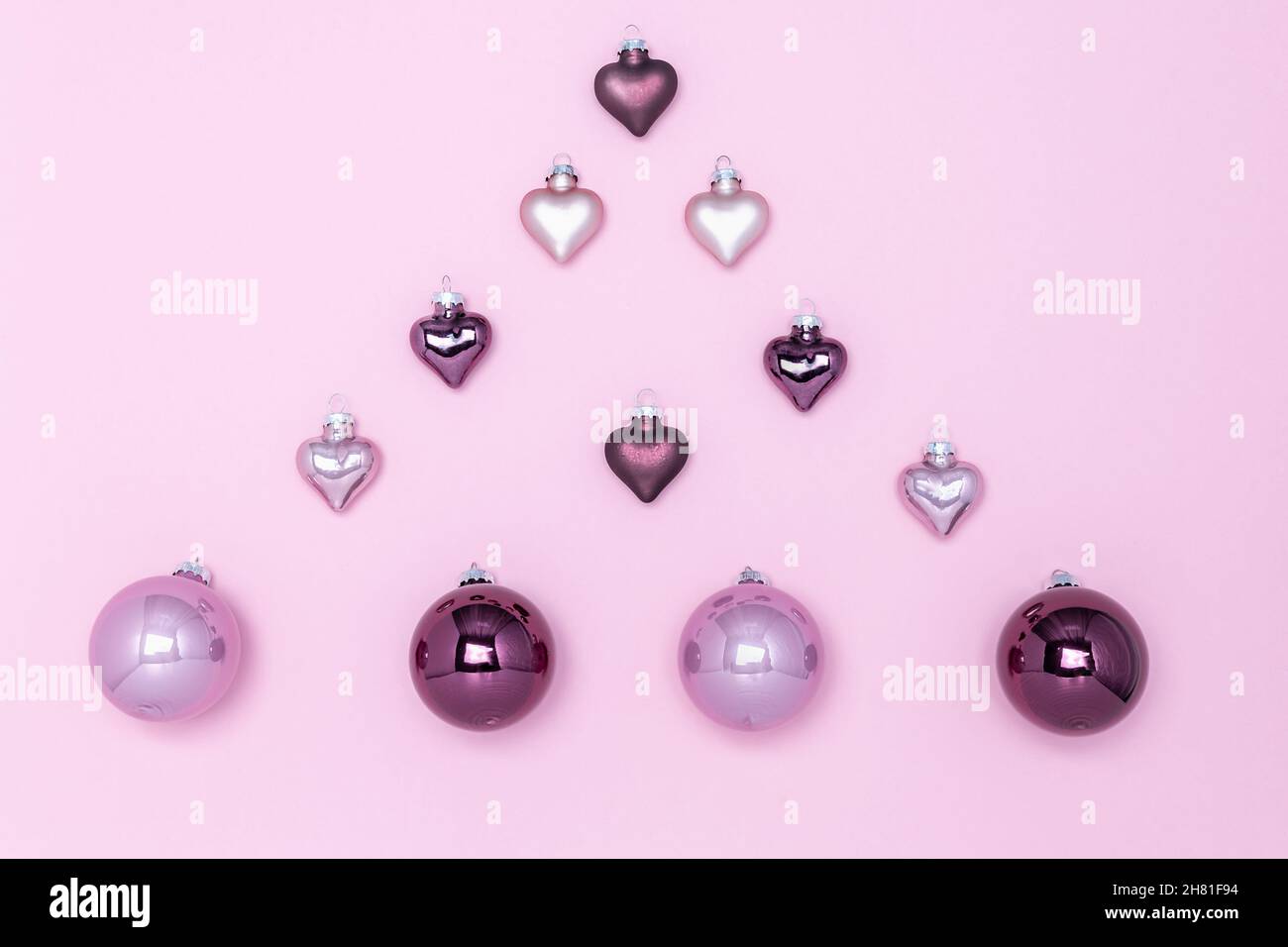Decorazioni dell'albero di Natale su sfondo rosa, disposte in forma di  abete. Lilla e palloncini viola e cuori. Biglietto di Natale Foto stock -  Alamy