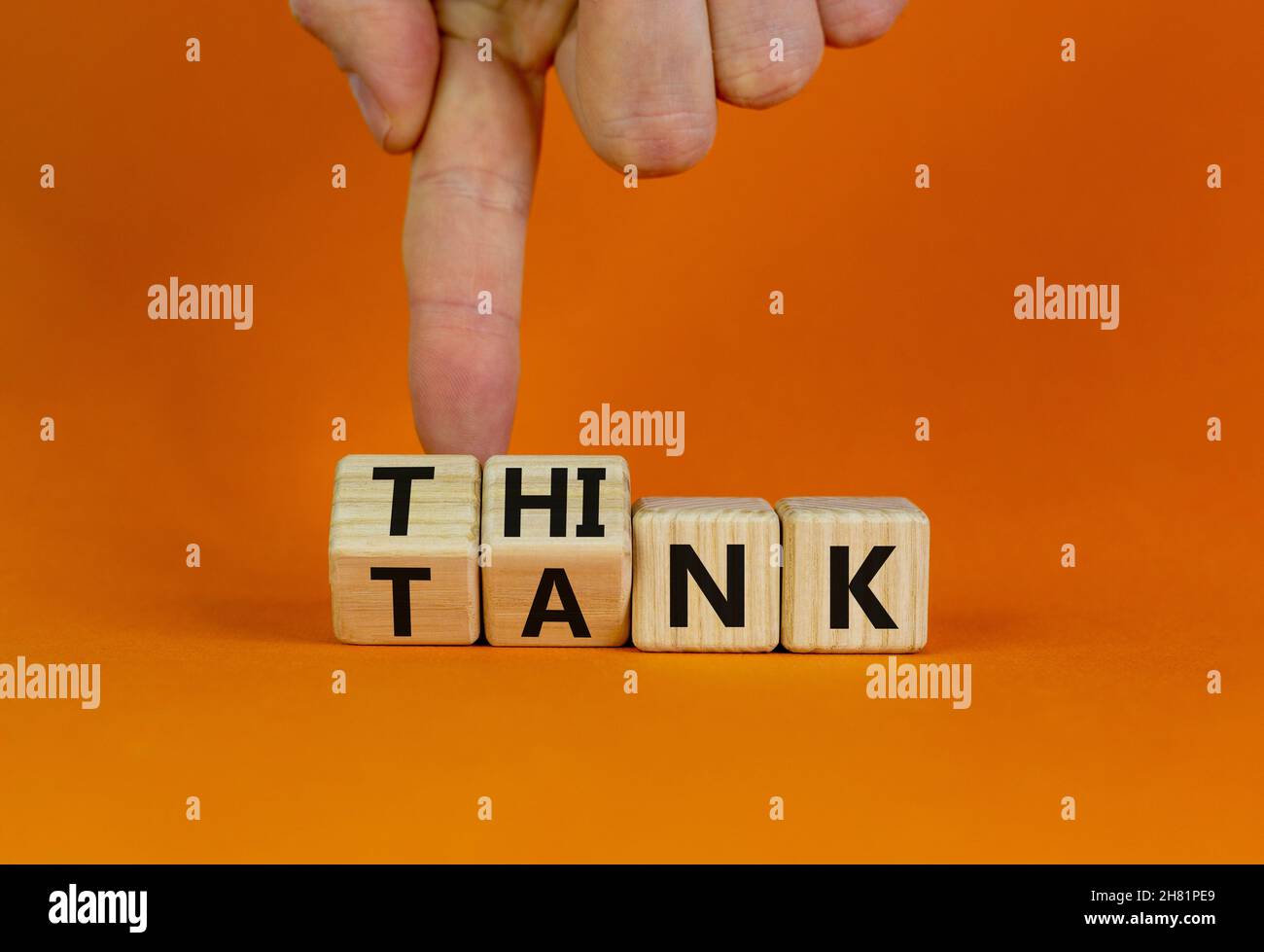 Think Tank. L'uomo d'affari trasforma i cubi di legno e cambia la parola 'serbatoio' in 'pensare' o viceversa. Bella tavola arancione, sfondo arancione, poliziotto Foto Stock