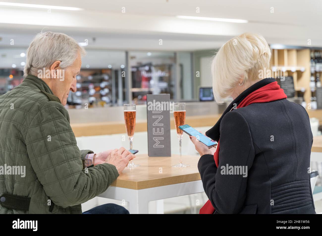 L'uomo e la donna che hanno una data oltre un drink in un ristorante non hanno potuto aiutare a controllare il proprio telefono cellulare per l'ultimo menu, London England UK Foto Stock