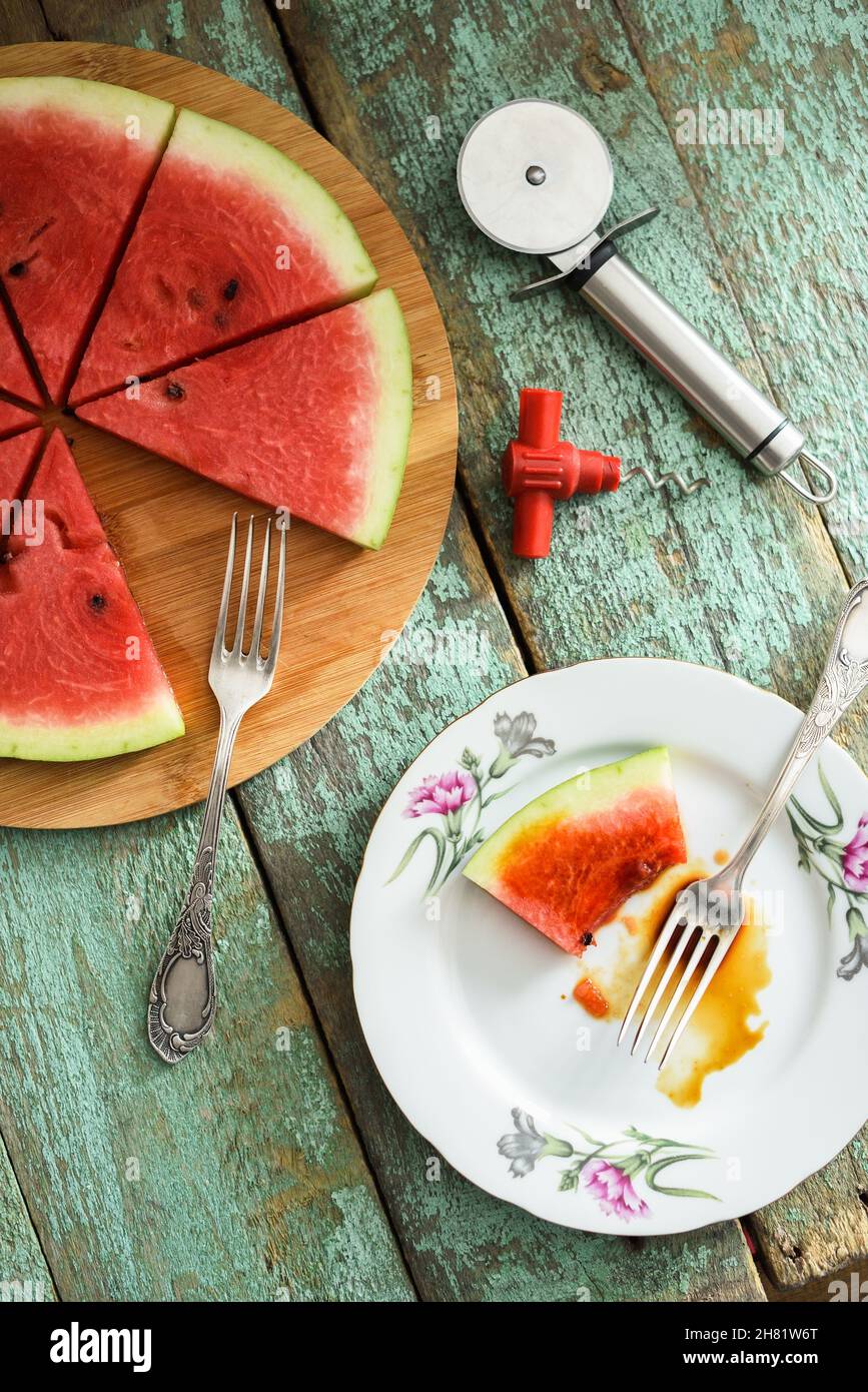 Cocomero fresco come pizza vegana con coltello per pizza e bouchon-pneumatico sul tavolo di legno shabby vista sopra Foto Stock