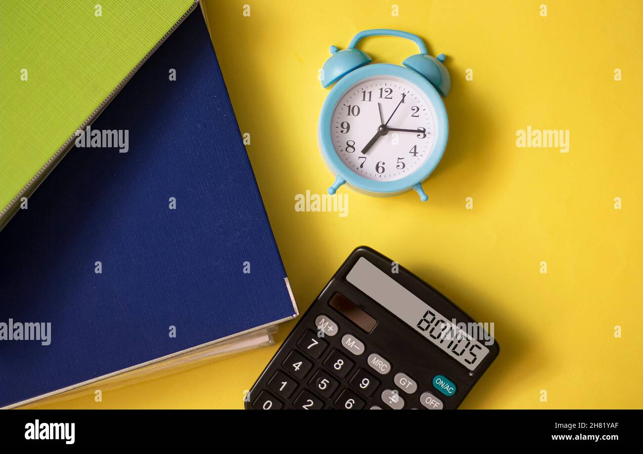 Calcolatrice con la parola BONDS in mostra con parchi documenti e orologio su sfondo giallo Foto Stock