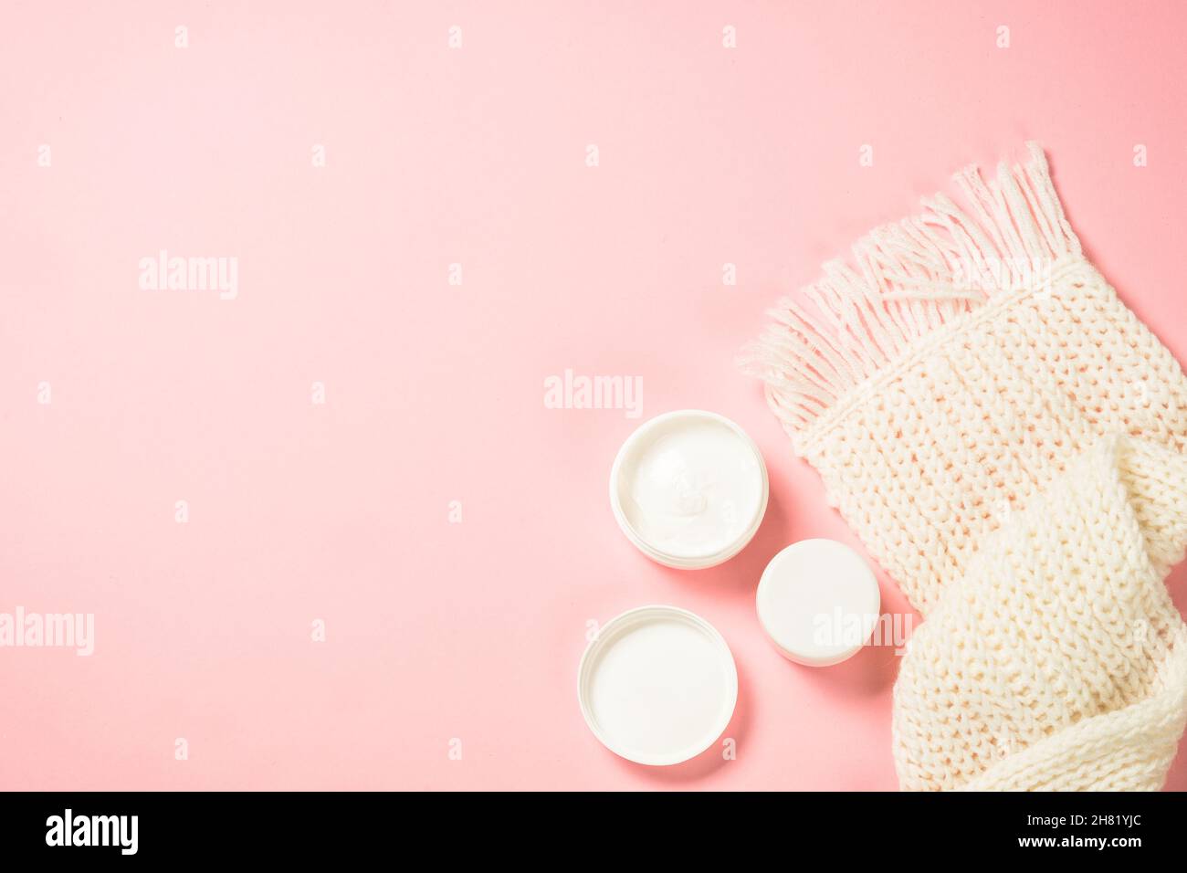 Sciarpa invernale cosmetica e in maglia a sfondo rosa. Foto Stock