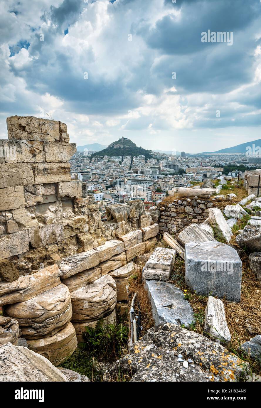 Antiche rovine greche sulla cima dell'Acropoli, Atene, Grecia. Vista spettacolare del Monte Lycabettus nel centro di Atene. Paesaggio urbano di Atene con tempeste Foto Stock