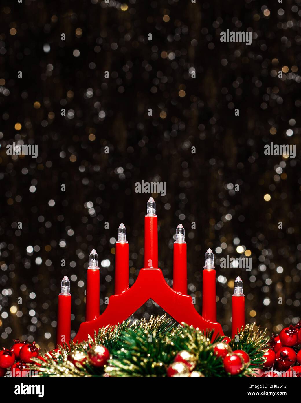 Decorazioni di Natale vista di rosso candela luci ponte, bacche rosse e Natale verde corona circolare colorato in oro alle punte su sfondo scuro wi Foto Stock