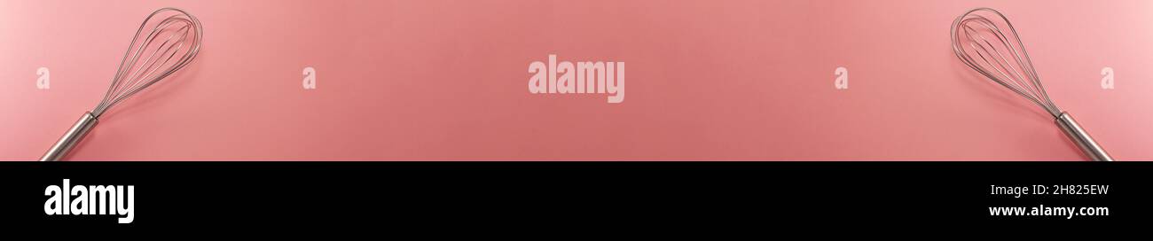 Striscione di due fruste in acciaio piatto vista dall'alto. Concetto di cucina dolciaria con spazio di copia su sfondo di carta rosa brillante Foto Stock