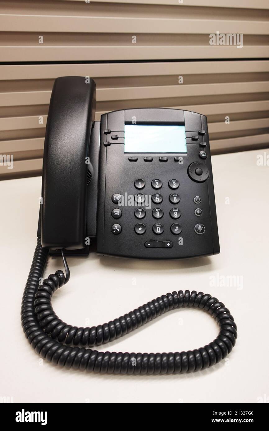 Telefono IP per ufficio nero sulla scrivania dell'armadio dell'ufficio Foto Stock
