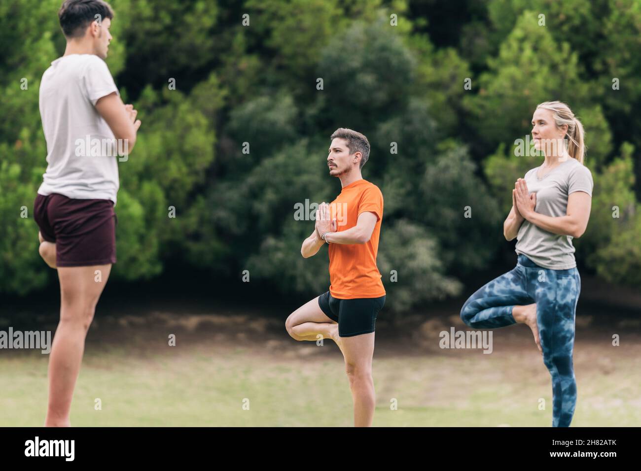 Tre persone che praticano lo yoga in un parco Foto Stock