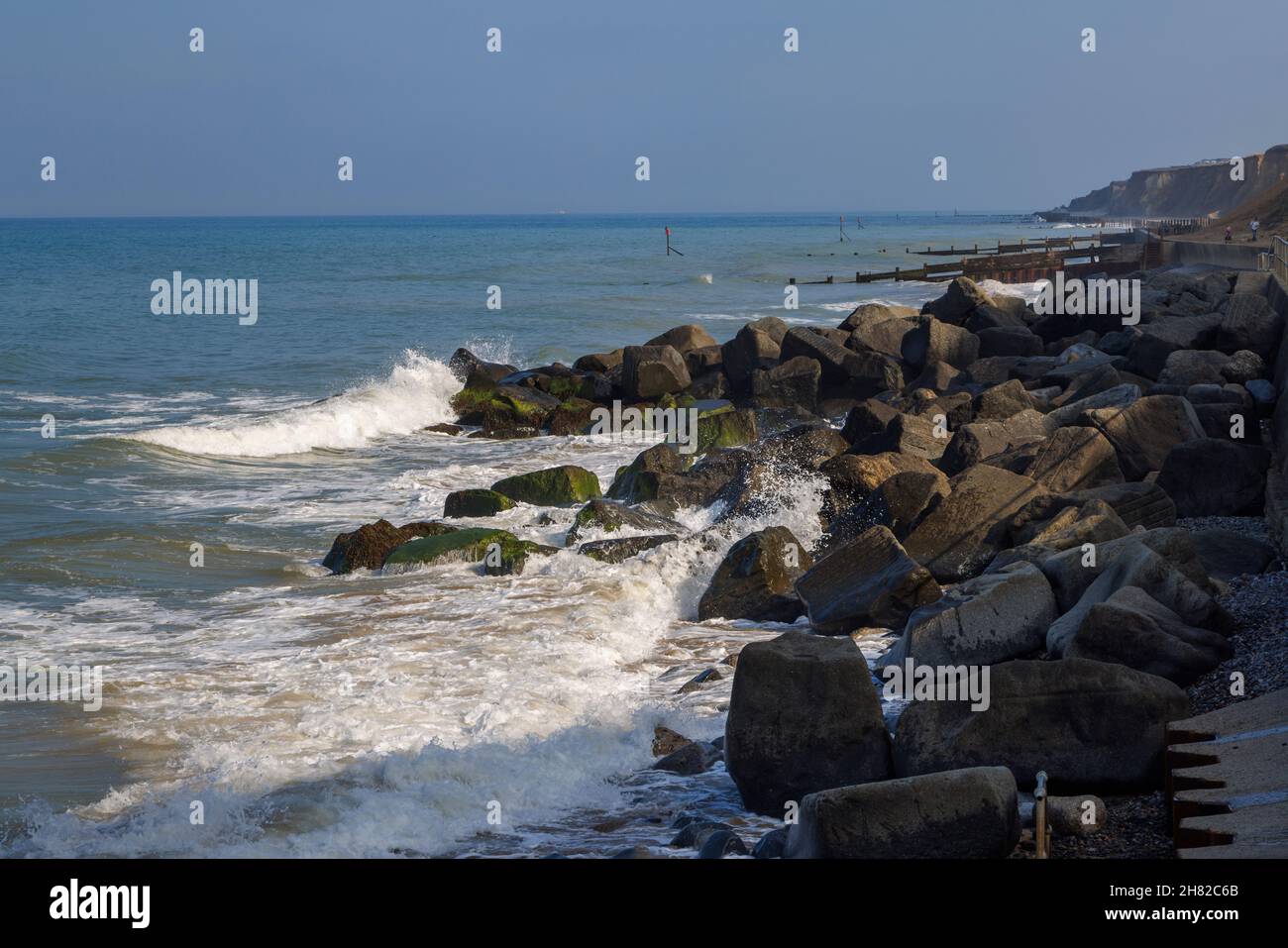 Le onde si infrangono su rocce protettive di frangiflutti sotto il lungomare di Sheringham, sulla costa nord di Norfolk, East Anglia, Inghilterra Foto Stock