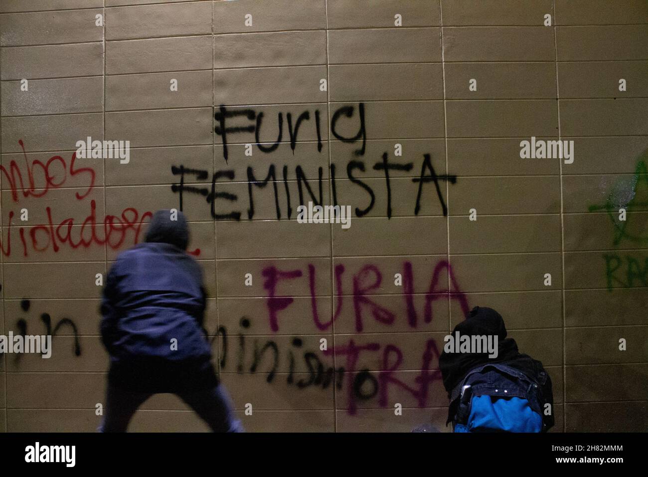 Un dimostratore graffia un muro con il messaggio 'Favura femminista' durante la Giornata Internazionale per l'eliminazione della violenza contro le donne dimostrazioni a Bogotà, Colombia il 25 novembre 2021. Foto Stock