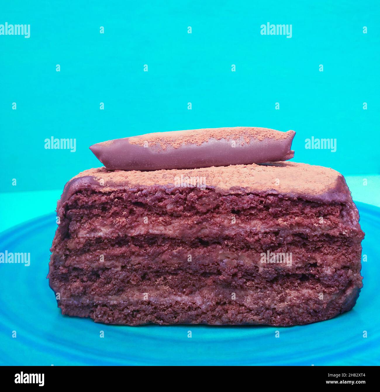 Vista laterale di una torta al cioccolato fondente su sfondo turchese Foto Stock