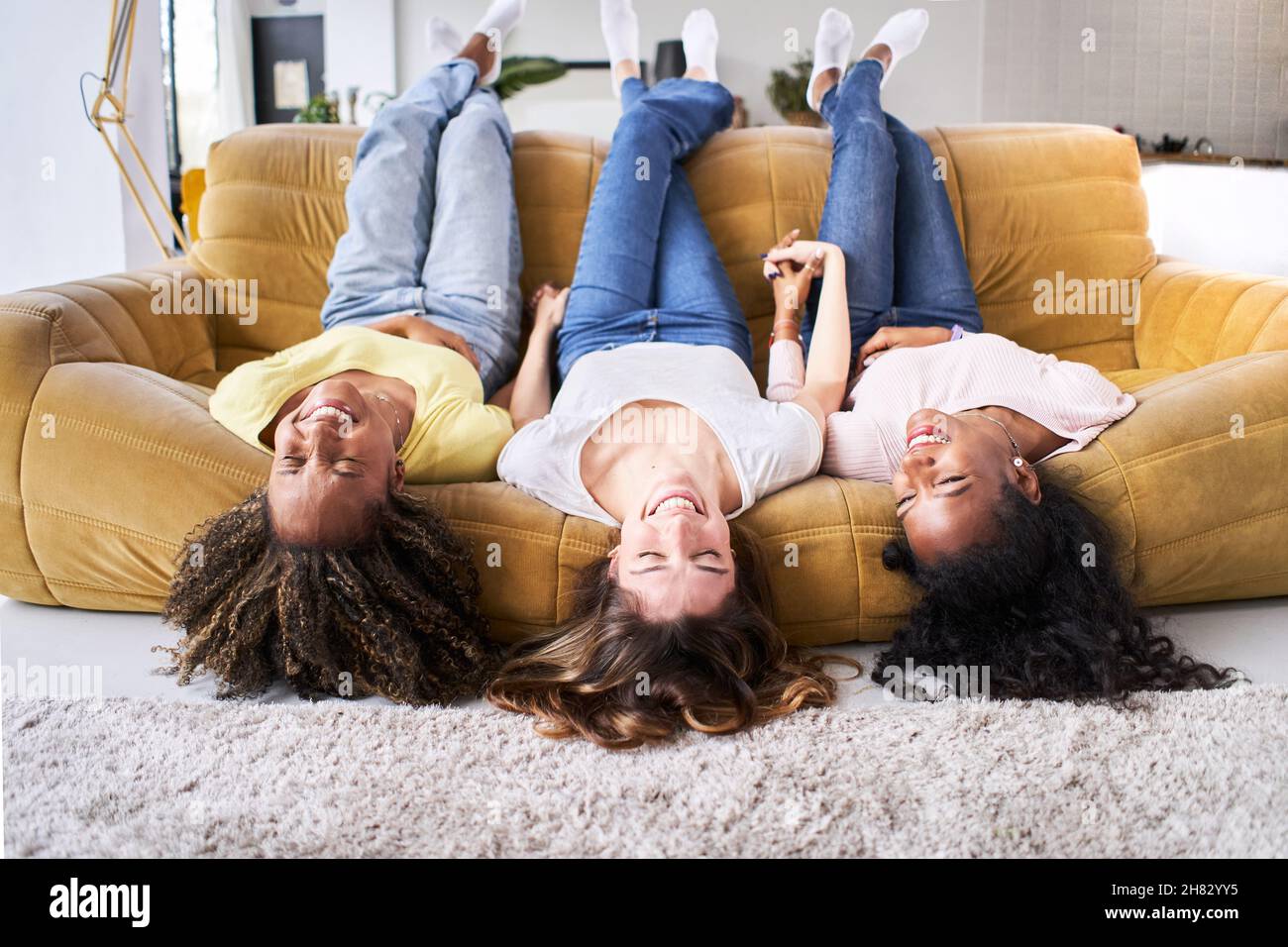Amicizia Donna felice sorridente a divano. I giovani che si divertono insieme a casa. Foto Stock