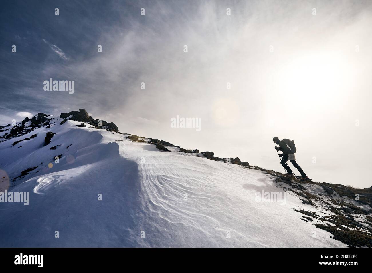 Uomo con zaino che sale in cima nel bellissimo paesaggio montano Foto Stock