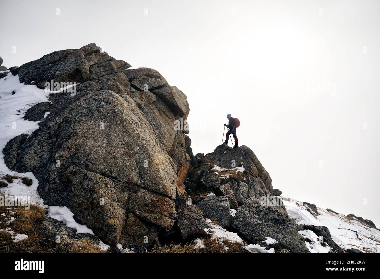 Uomo con zaino che sale in cima nel bellissimo paesaggio montano Foto Stock