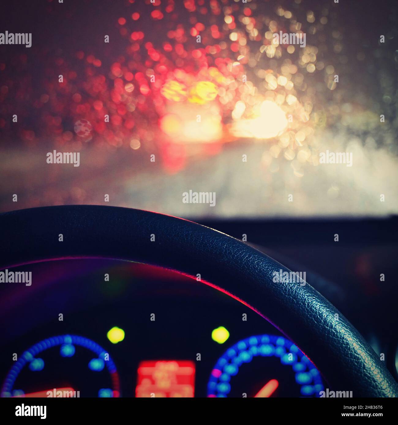 Stagione invernale pericolosa con neve su strada. L'interno dell'auto dal punto di vista del conducente - pericoloso traffico serale in cattive condizioni meteorologiche. Foto Stock