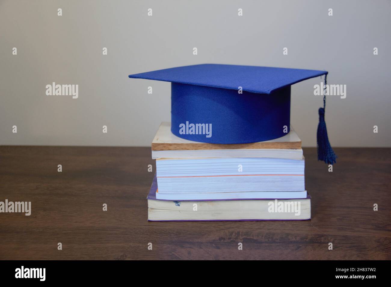 Tappo graduato, isolato, sopra una pila di libri su un tavolo di legno con sfondo bianco. Foto Stock