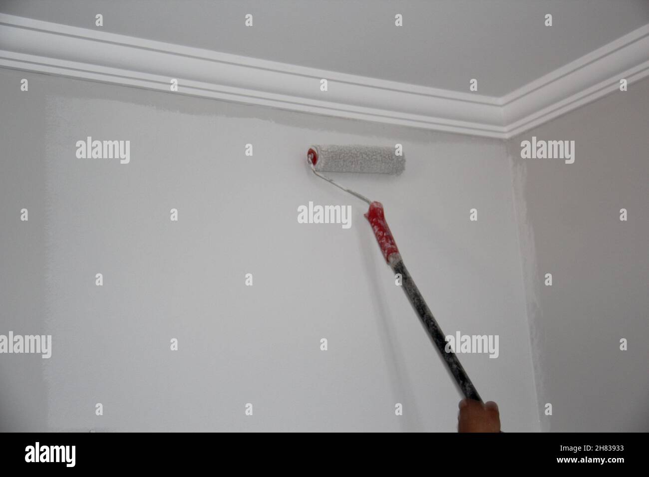 Maschio pittura a mano una parete con una spazzola a rullo. Foto Stock