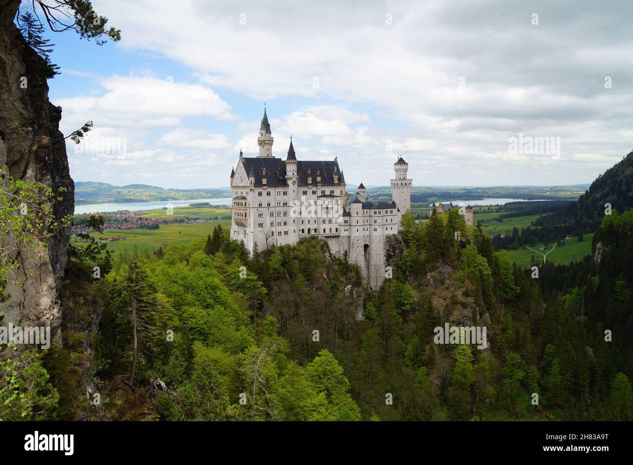 Castello bavarese Neuschwanstein nelle Alpi e lago Forggensee sullo sfondo fotografato dal ponte Marienbruecke (Baviera, Germania) Foto Stock