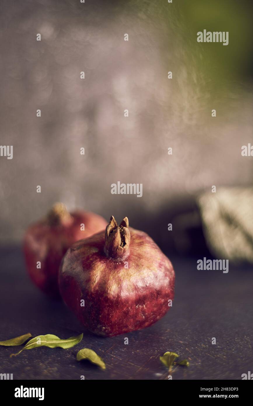 Melograno maturo e foglie di melograno su sfondo grigio. Foto Stock