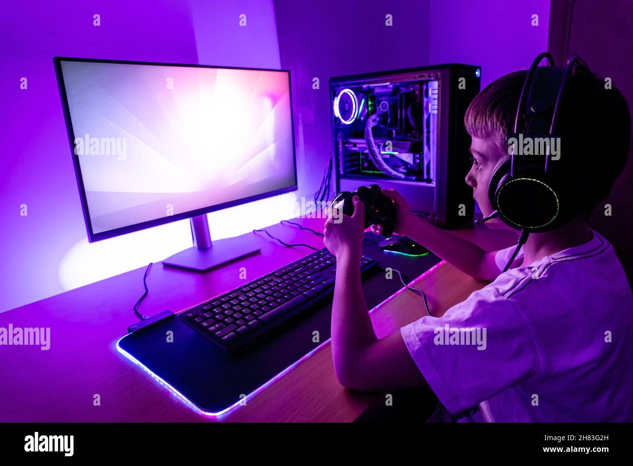 I giocatori giocano con il PC con il joypad. Moderna configurazione di gioco con custodia di raffreddamento ad acqua, joypad, mouse, cuffia. Foto Stock