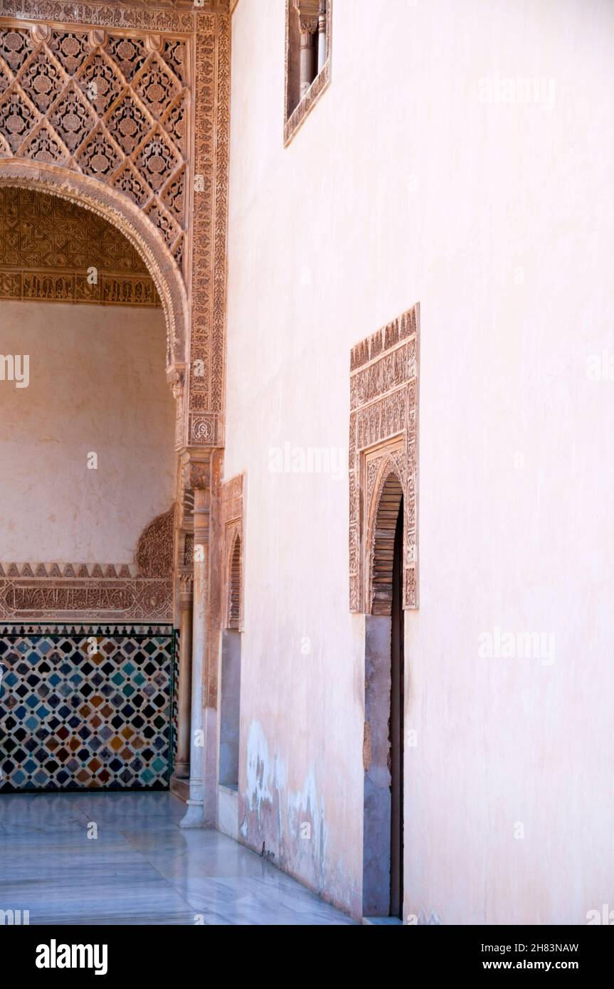 Ingressi ad arco dentati, piastrelle a mosaico geometrico e calligrafia moresca all'Alhambra di Granada, Spagna. Foto Stock