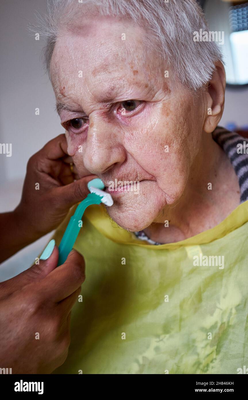 donna anziana che riceve la rimozione dei capelli del viso da un operatore sanitario afroamericano Foto Stock