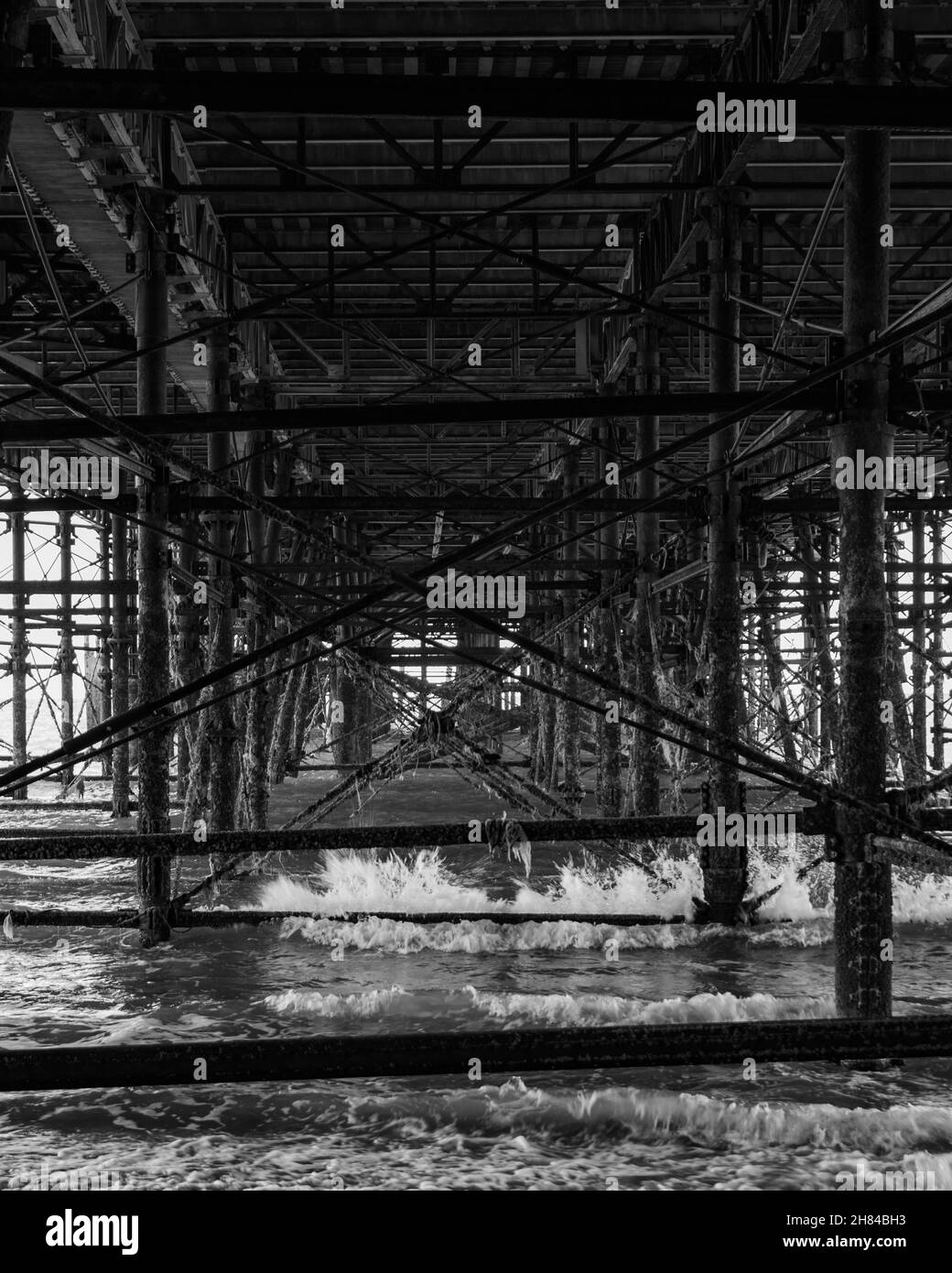 Onde piccole e medie che si infrangono contro la parte inferiore di Hastings Pier, Sussex, UK. Foto Stock