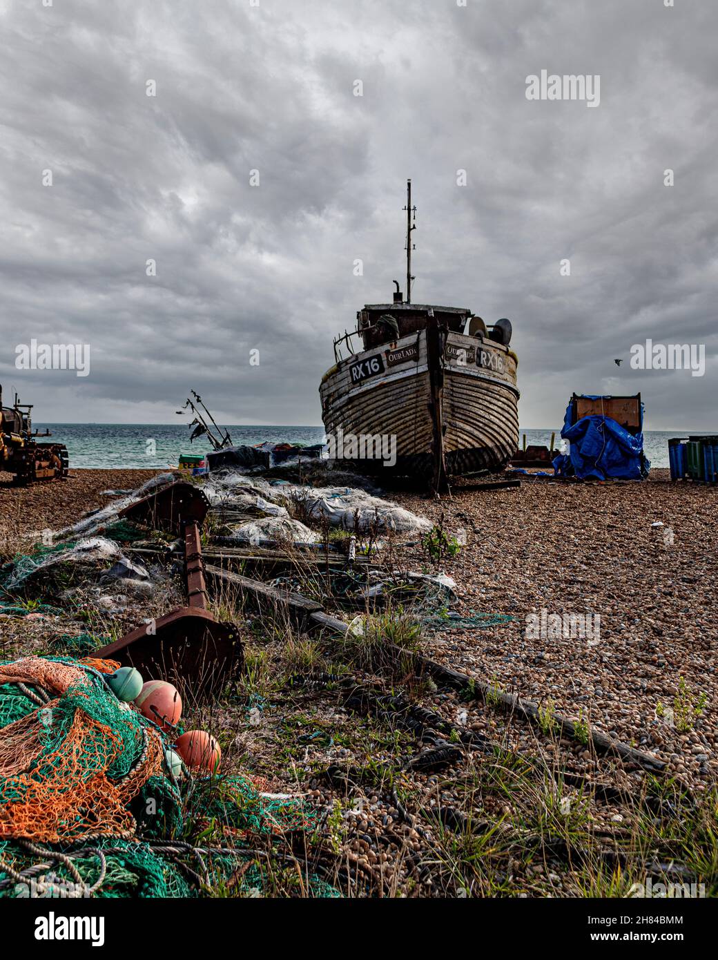 Una barca decadente con vernice rossa e il numero rx258 sotto il cielo nuvoloso sulla spiaggia di Hastings, città vecchia di Hastings preso sotto il cielo nuvoloso Foto Stock