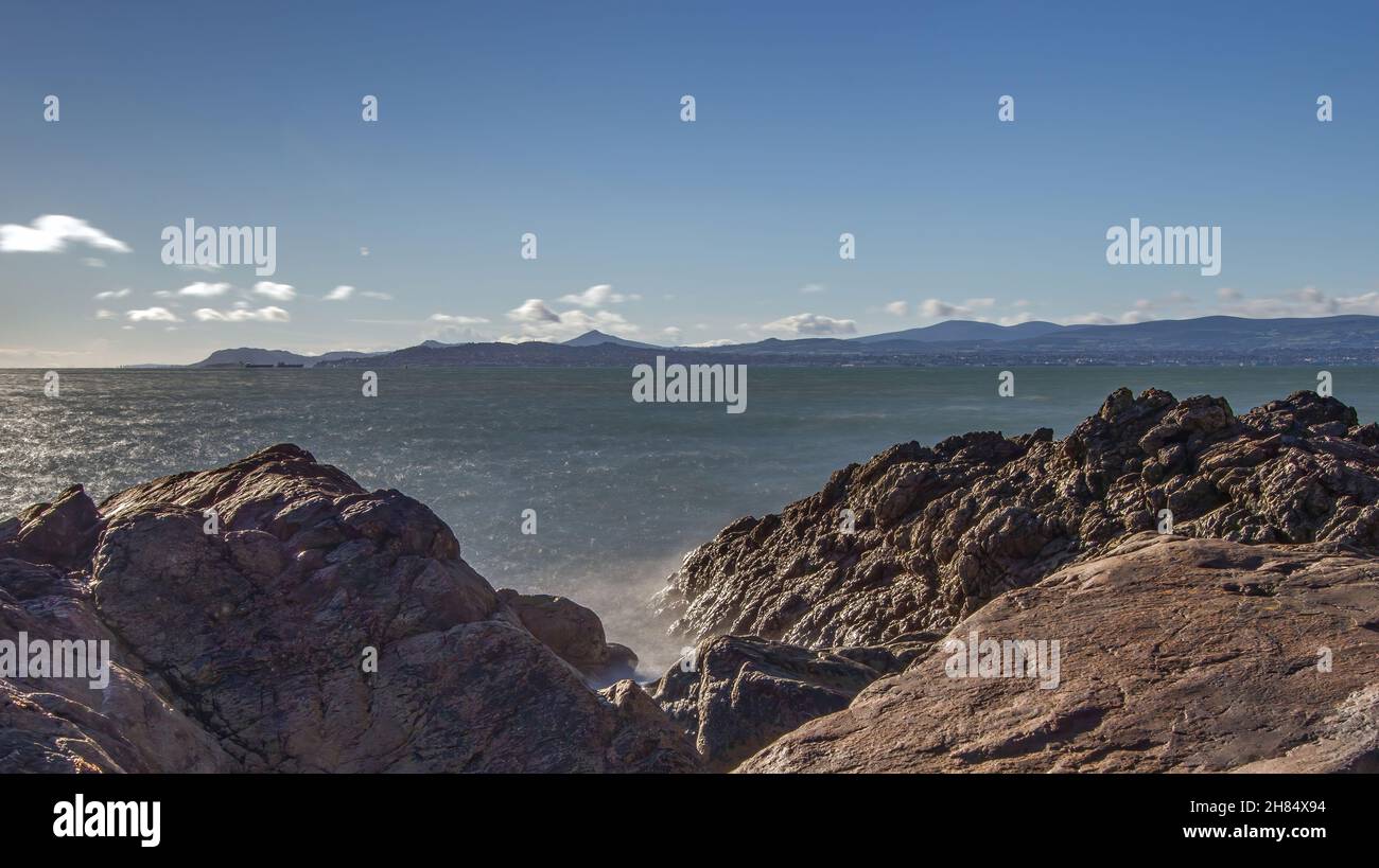La penisola di Howth Head in giornata soleggiata e nuvolosa, esposizione a lungo, Dublino County, Seashore di scogliere, baie e rocce paesaggio, Irlanda Foto Stock