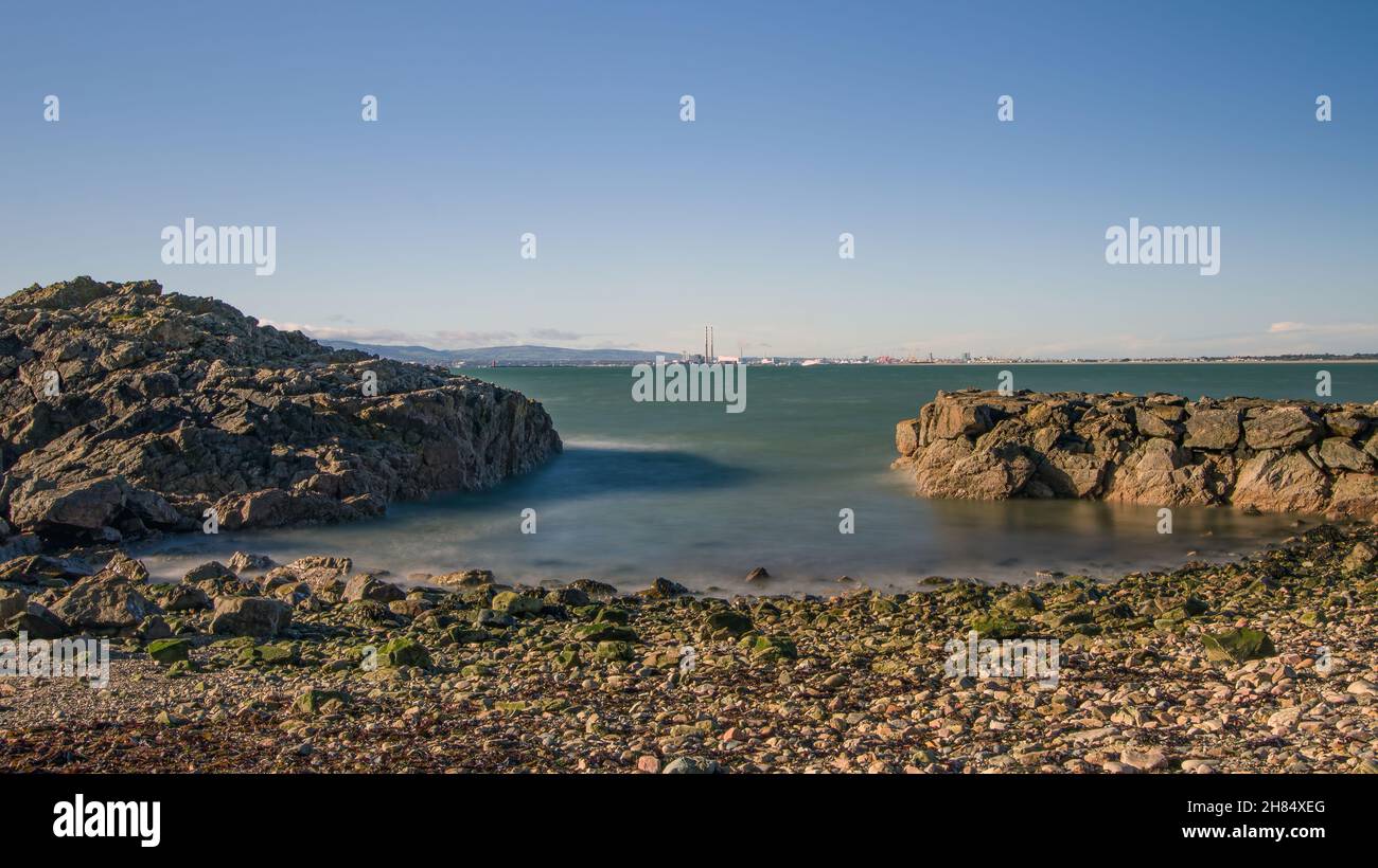 La penisola di Howth Head in giornata soleggiata e nuvolosa, esposizione a lungo, Dublino County, Seashore di scogliere, baie e rocce paesaggio, Irlanda Foto Stock