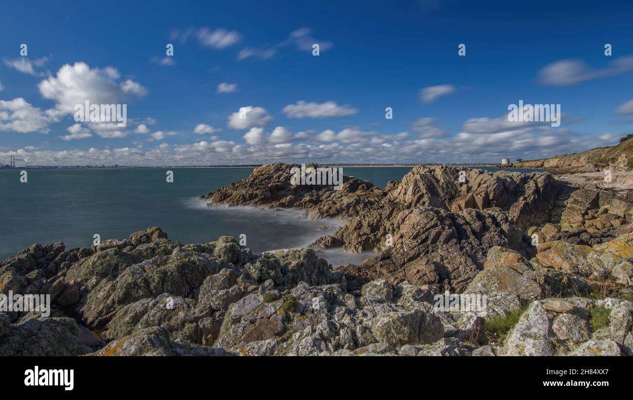 La penisola di Howth Head in giornata soleggiata e nuvolosa, esposizione a lungo, Dublino County, Seashore di scogliere, baie e rocce paesaggio, Irlanda Foto Stock