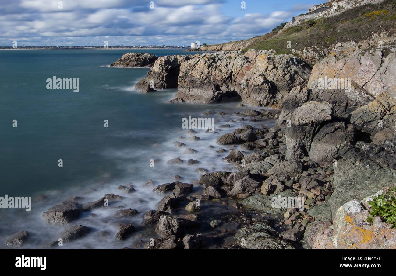 La penisola di Howth Head in giornata soleggiata e nuvolosa, esposizione a lungo, Dublino County, Seashore di scogliere, baie e rocce paesaggio, Irlanda Foto Stock
