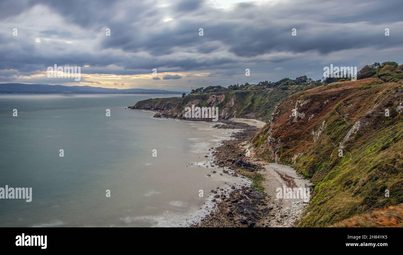 La penisola di Howth Head in giornata soleggiata e nuvolosa, esposizione a lungo, Dublino County, Seashore di scogliere, baie e rocce paesaggio, Irlanda Foto Stock