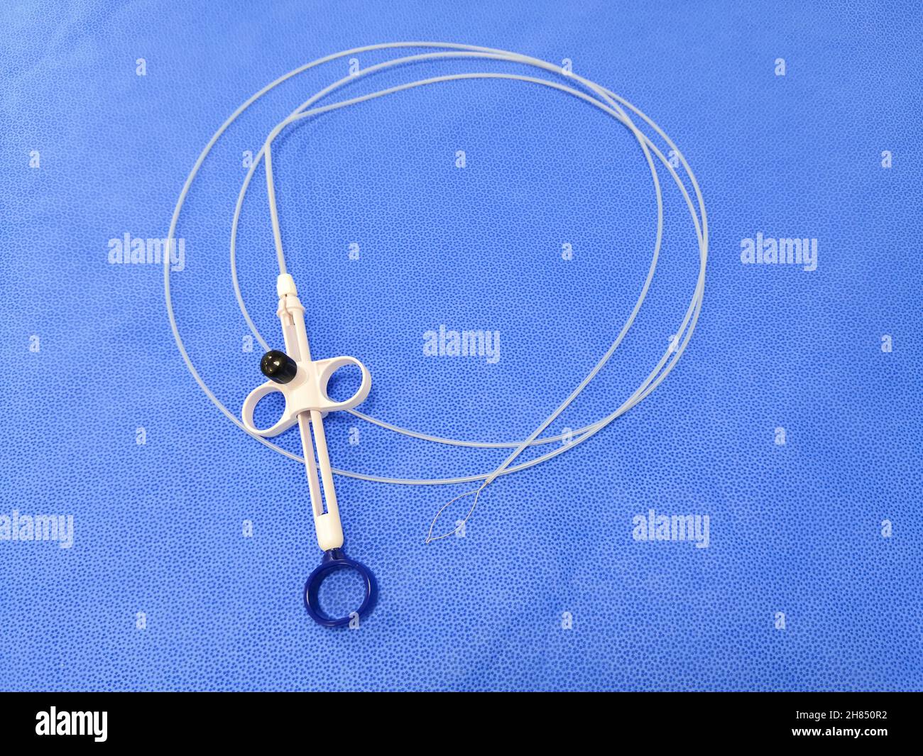 Primo piano immagine dello strumento endoscopico polipectomia Snare su sfondo blu. Messa a fuoco selettiva Foto Stock