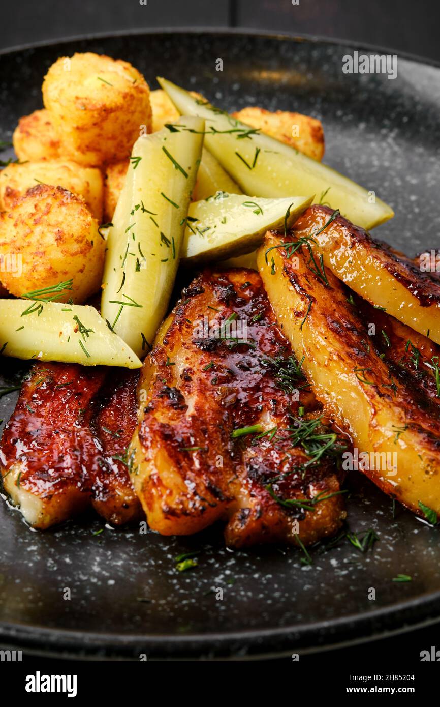 Primo piano di vista della pancia di maiale arrosto con palle di patate e cetriolo sottaceto su un piatto Foto Stock