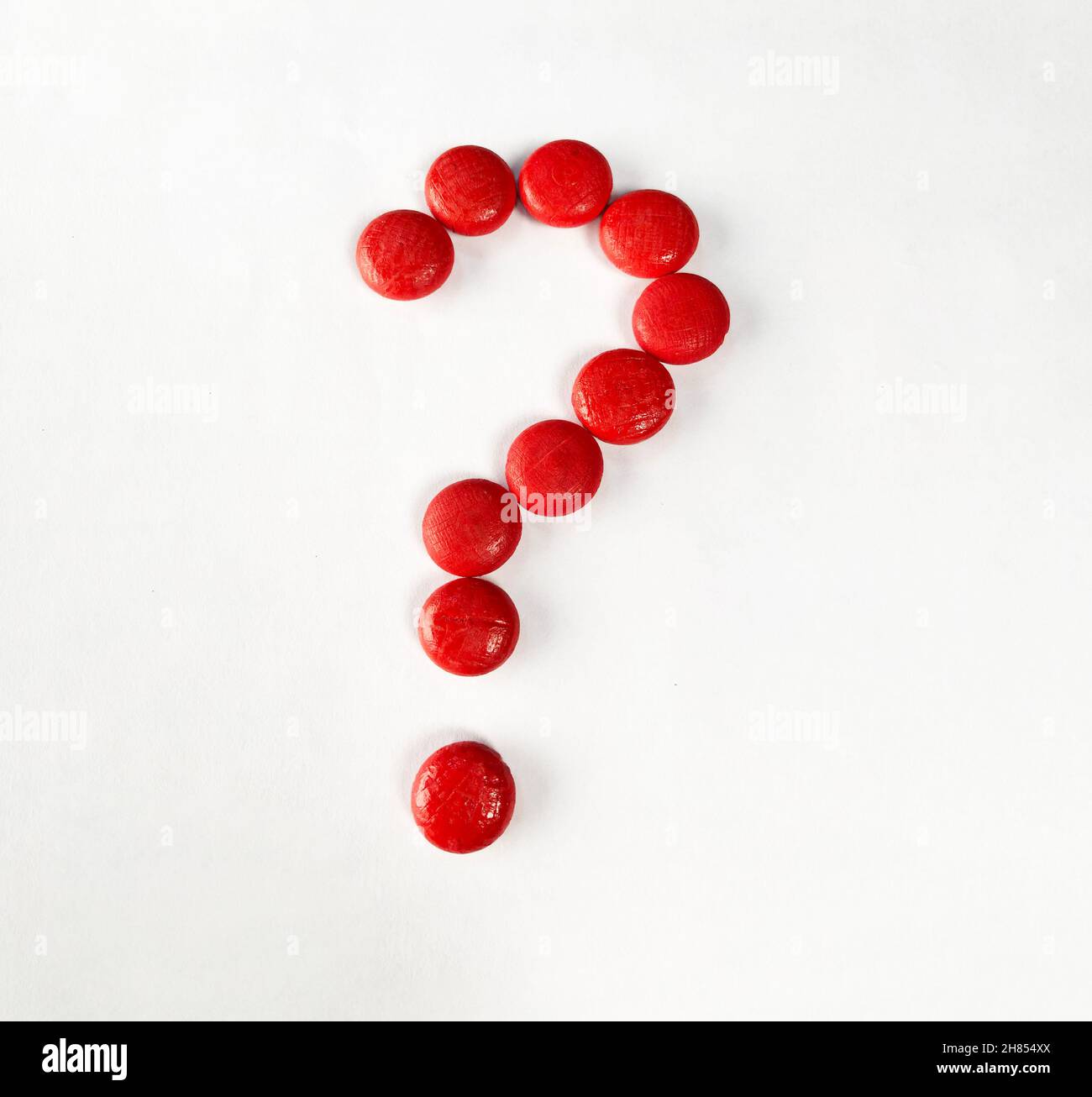 Punto interrogativo con piccoli oggetti di legno rossi su carta bianca. Foto Stock