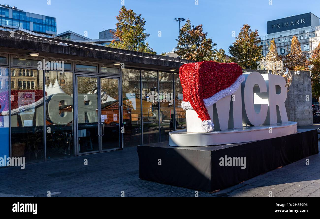 MCR con Santa Hat e Golden Manchester Bee in mostra con finestra relflection in Piccadilly Gardens, Manchester, Inghilterra, Regno Unito. 2021 Foto Stock