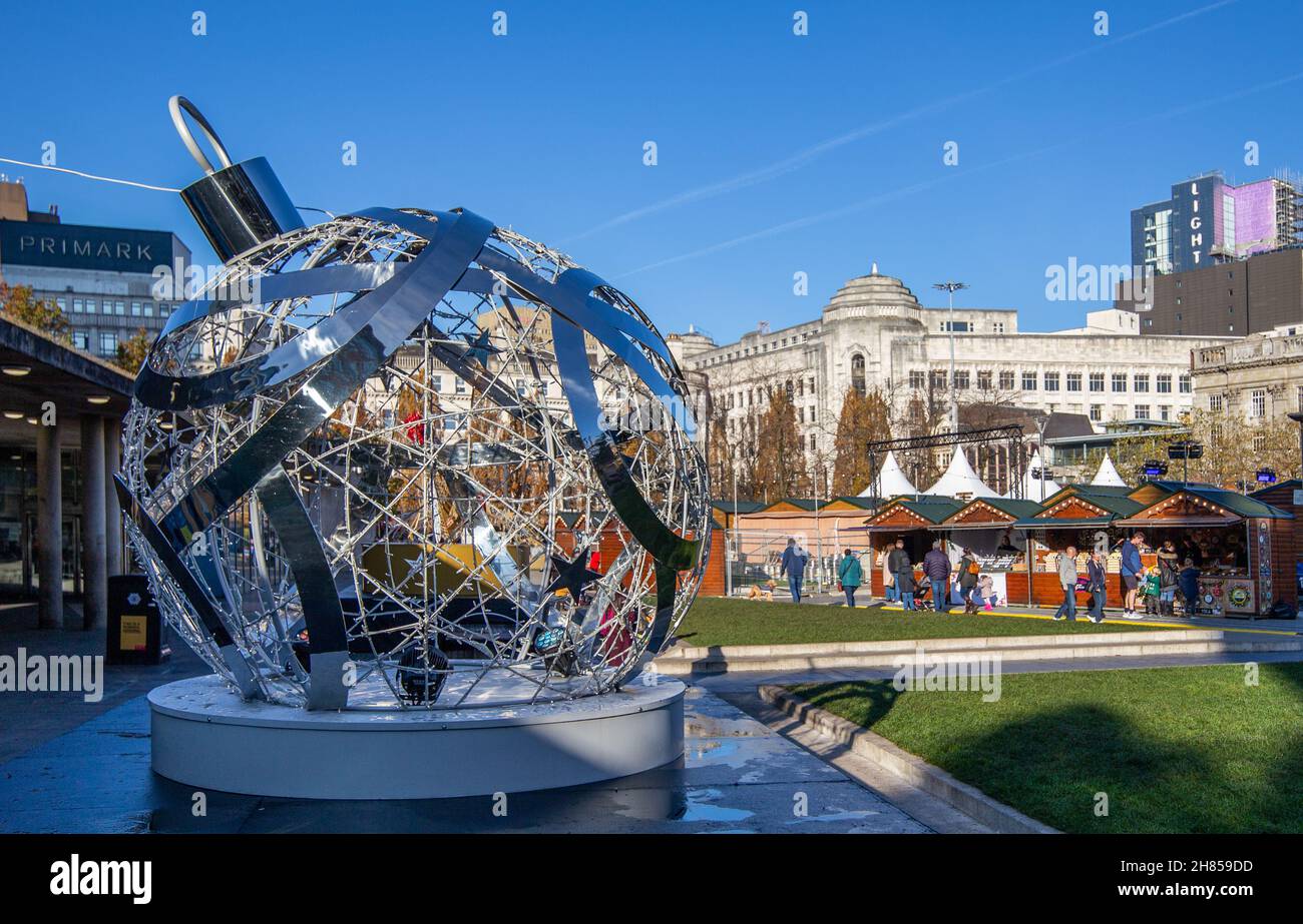 Una grande decorazione bauble di Natale di fronte al mercato di Natale bancarelle in Piccadilly Gardens, Manchester, Inghilterra, Regno Unito, 2021 Foto Stock