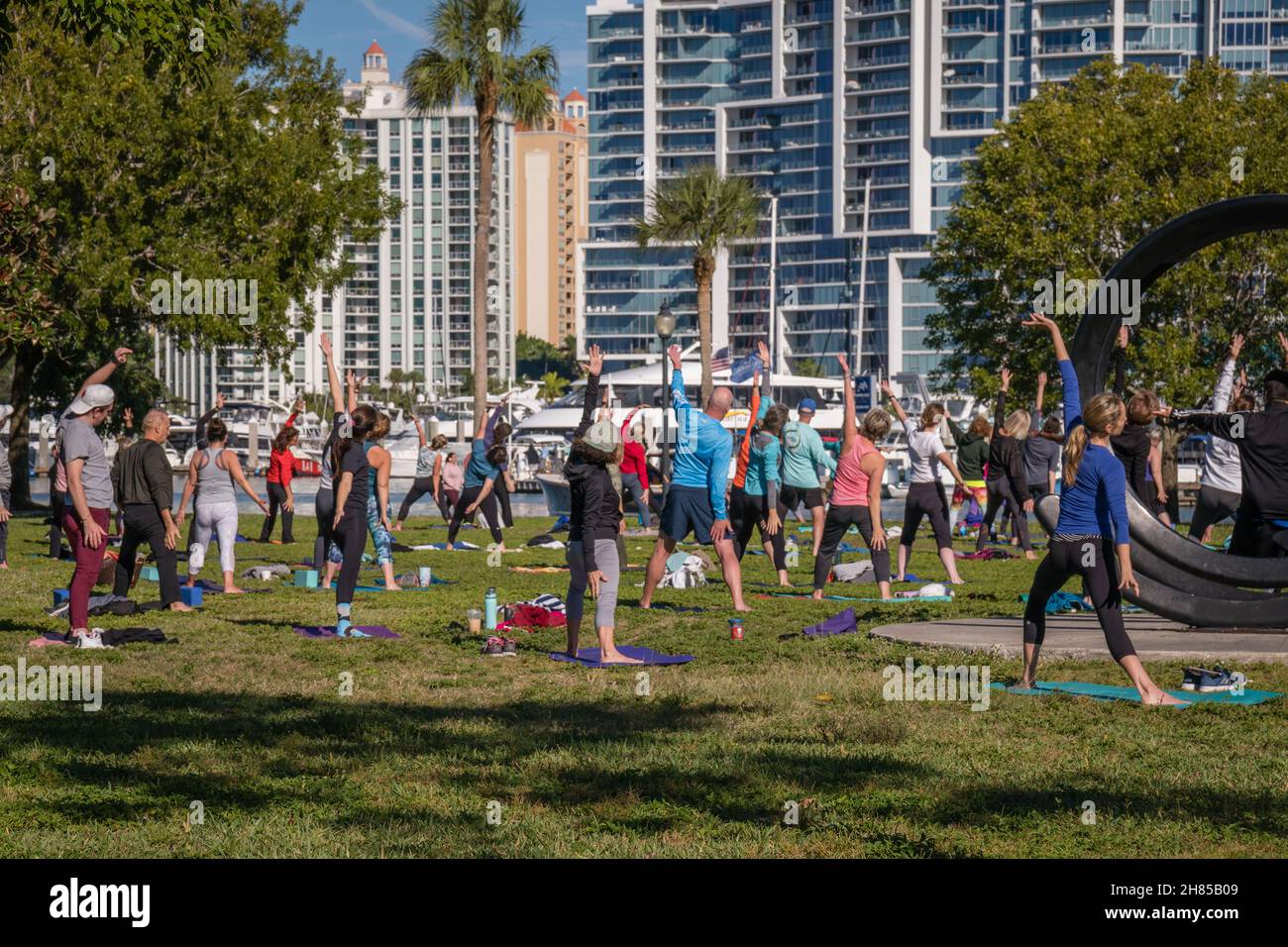 Sarasota, Florida, US-27 novembre 2021: Grande lezione di yoga all'aperto nel parco Bayfront vicino al porticciolo e all'acqua. Foto Stock